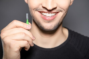 man hold handle of interdental brush in his hands and smile into camera ready to clean space...