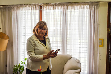 older woman in the comfort of her home using her smartphone to connect with new technologies