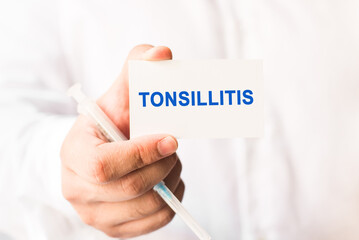 Word tonsillitis on a white background with a syringe in hand. Medicine concept