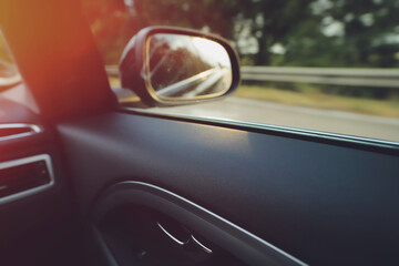 inside view on door panel and passenger side window of a fast moving modern upper-middle class car in bright leaking sunlight - motion blur on landscape shallow depth of field