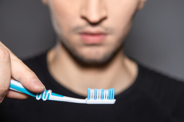 empty toothbrush in hand of a man holding it high up to his serous face