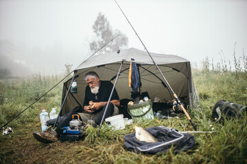 Mature man camping and preparing coffee on camping stove