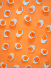 Boiled orange half cut eggs pattern on orange background