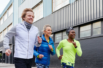 Smiling mature friends running together
