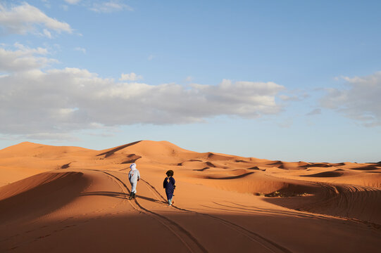 Berber tribe males walk sand dunes