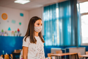 Elementary schoolchildren wearing a protective face masks  in the classroom. Education during epidemic.