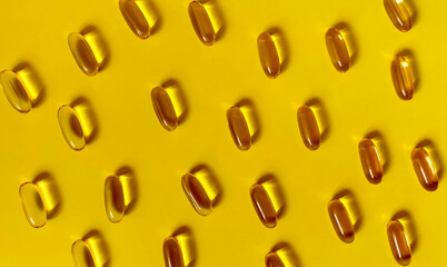 Flat lay Oil capsules on yellow background.  Omega, vitamin D capsules. Hard shade pattern.  Background texture.
