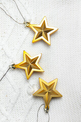 Fototapeta premium Christmas toys stars are Golden . Golden Christmas toys. White knitted fabric. New year and Christmas holidays. Christmas layout on top. Article about the holiday.