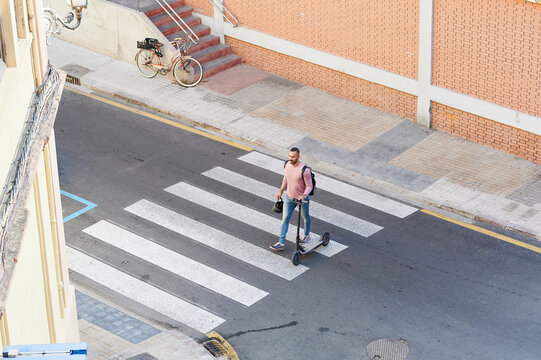 Man with a scooter crossing the street