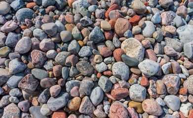 Sea pebbles on the sand. Small smooth stones. Stony seashore.