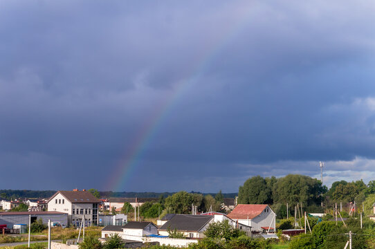 Rainbows in the sky. Rain clouds and rainbows. Rainbows over the roofs of houses.