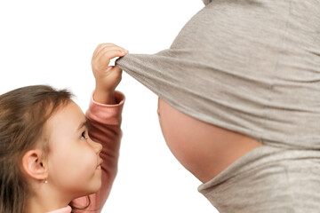 Little girl looks at pregnant mom's belly