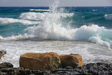 Big waves with splashes run on the shore with rocks