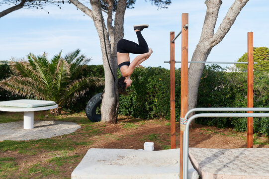 Fit girl doing a flip off parallel bars