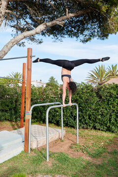 Fit woman doing a handstand on parallel bars