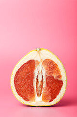 Grapefruit minimal erotic concept. Half a juicy grapefruit close up on a colored background.