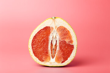 Grapefruit minimal erotic concept. Half a juicy grapefruit close up on a colored background. - obrazy, fototapety, plakaty