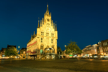 City hall on the market square in the old town of Gouda, Holland is illuminated in the evening hours