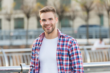 happy handsome guy with nice smile wearing casual checkered shirt outdoor and has bristle on unshaven face, male fashion and grooming
