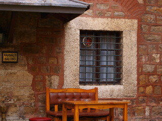 Fototapeta na wymiar A wooden table with a bench in front of the window of an old building made of stone and brick and a 