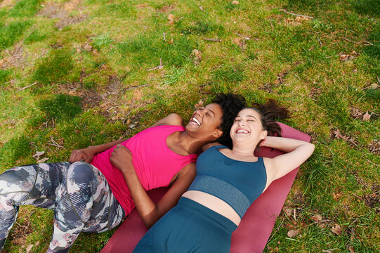 Laughing friends lying on a mat after yoga
