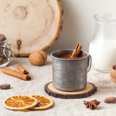 Hot chocolate in a metal mug with a cinnamon stick on the tablecloth. Copy space