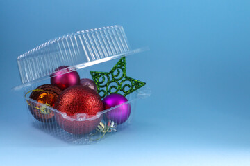 Plastic container with Christmas toys on color background
