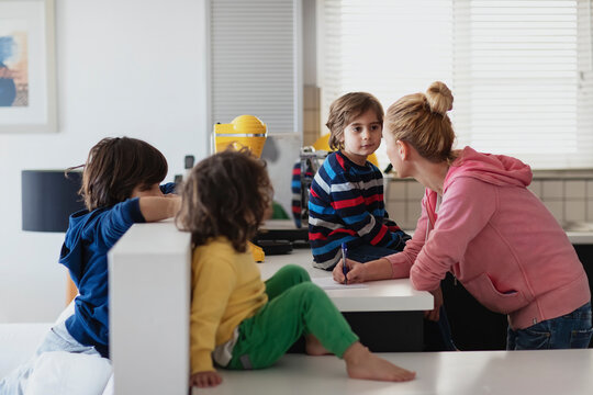 Young woman creating a shopping list for grocery with some suggestions from her kids...