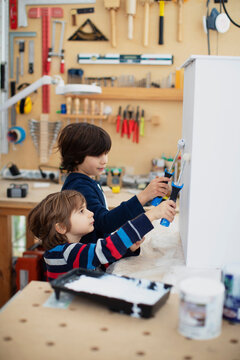 Five year old boy with his nine year old brother painting a wooden box