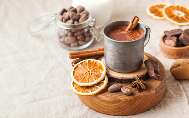 Hot chocolate in a metal mug with a cinnamon stick on the tablecloth. Copy space