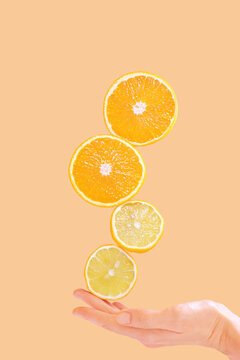 Cut in half lemons and oranges and a woman's hand on a pastel background. Surreal levitation effect. Citrus, vitamin C, fruit concept.