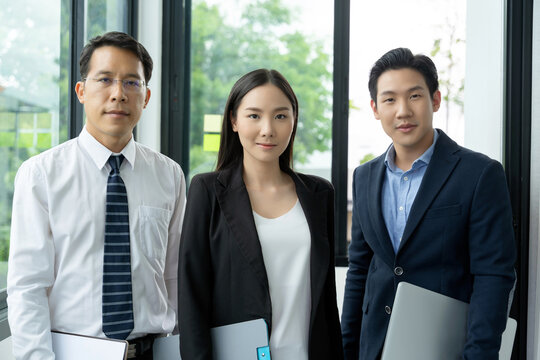 Portrait of three asian business men and woman are standing with a confidence. A teamwork businessman who standing at the office. Asian professional business people are standing with friendly face.