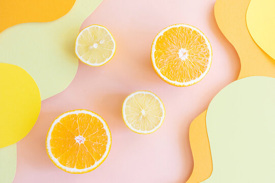 Halved lemons and oranges on vibrant colored wave backgrounds. Paper art style on photo. Concept of citrus, vitamin C, fruit.