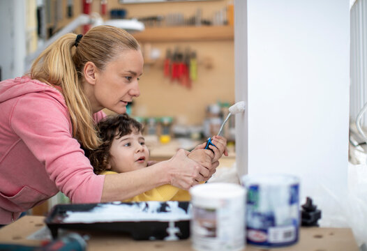 Mother with her 2 year old boy painting a wooden box