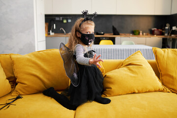 Funny child girl dressed in witch canival costume. Halloween holiday during quarantine time