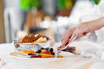 woman eating breakfast in bed. Fresh croissant bread fruits in plate