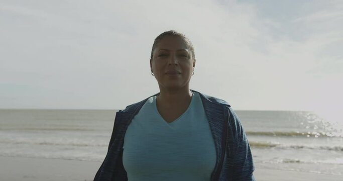Portrait of Body positive mature black female model outdoors on beach, Plus size obese overweight Afro American woman looking at camera at sunrise