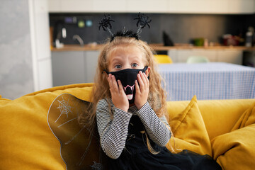 Funny child girl dressed in witch canival costume. Halloween holiday during quarantine time