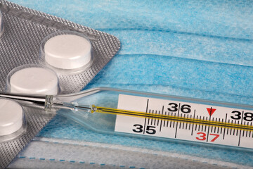 thermometer and pills on medical mask