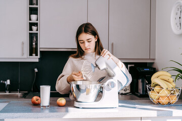 Teenager girl using mixer or food processor making dough.  Child cooking at modern kitchen,...