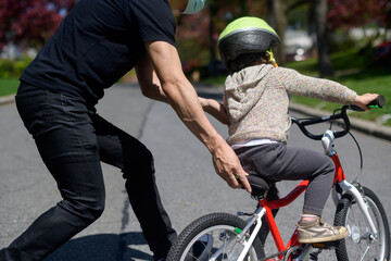 Dad teaching child to ride a bike