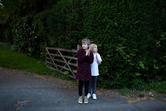 Brother and sister stand on the street clapping for essential workers
