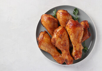 Roasted chicken drumsticks in honey and soy sauce on grey plate, top view, with space for text