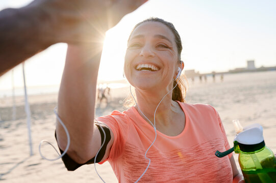 Fit woman high fiving a partner on a beach