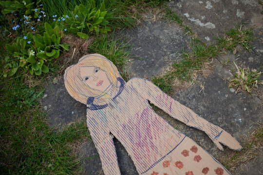 A cardboard person lies on the ground
