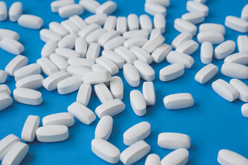 many white clean pills tablets lying on blue surface