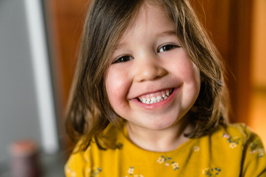 Crop smiling little child in casual clothes at home