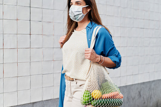 Woman in a face mask walking with a shopping bag