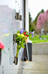 Flowers in a vase on the mausoleum wall - obrazy, fototapety, plakaty