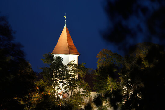 Illuminated cityscape at night, church tower and spire close-up. Old town of Talsi, Latvia. Travel destinations, vacations, tourism, landmarks, sightseeing, culture and religion